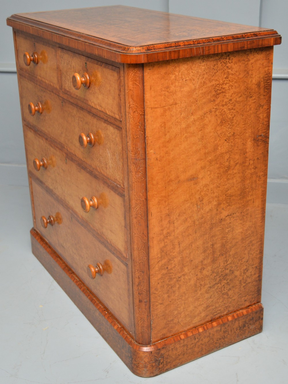 A Victorian satinwood chest of drawers featuring two small upper drawers above three full-width drawers with turned rosette knobs and a plinth base. View XXVII