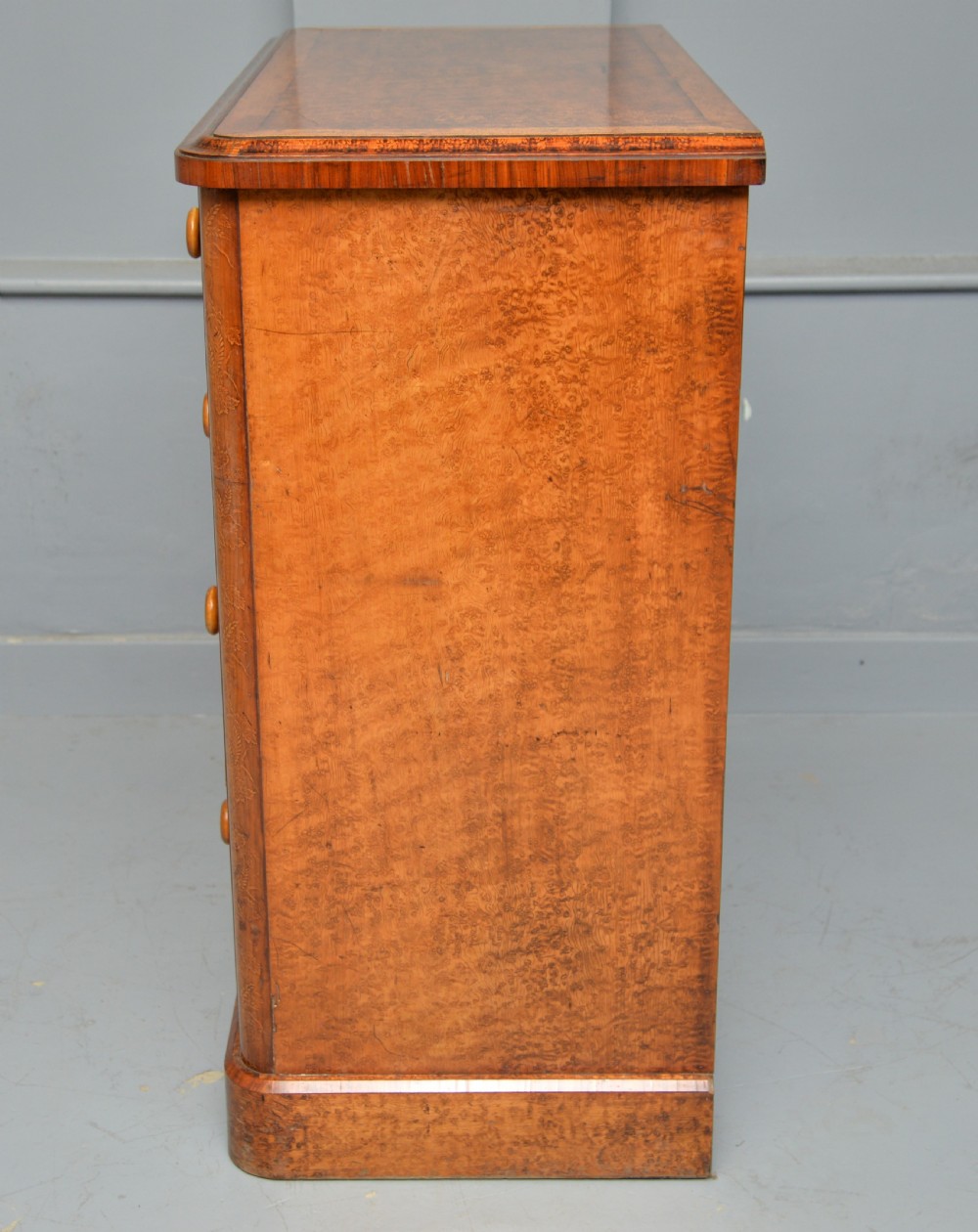 A Victorian satinwood chest of drawers featuring two small upper drawers above three full-width drawers with turned rosette knobs and a plinth base. View XXIX