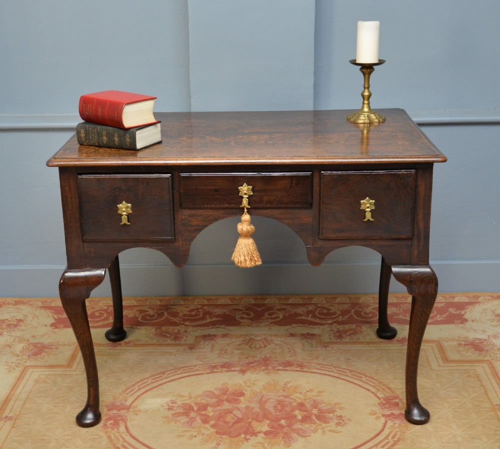 An early 18th-century George I dark oak lowboy featuring three drawers with brass handles, a shaped kneehole apron, and cabriole legs ending in pad feet. View III