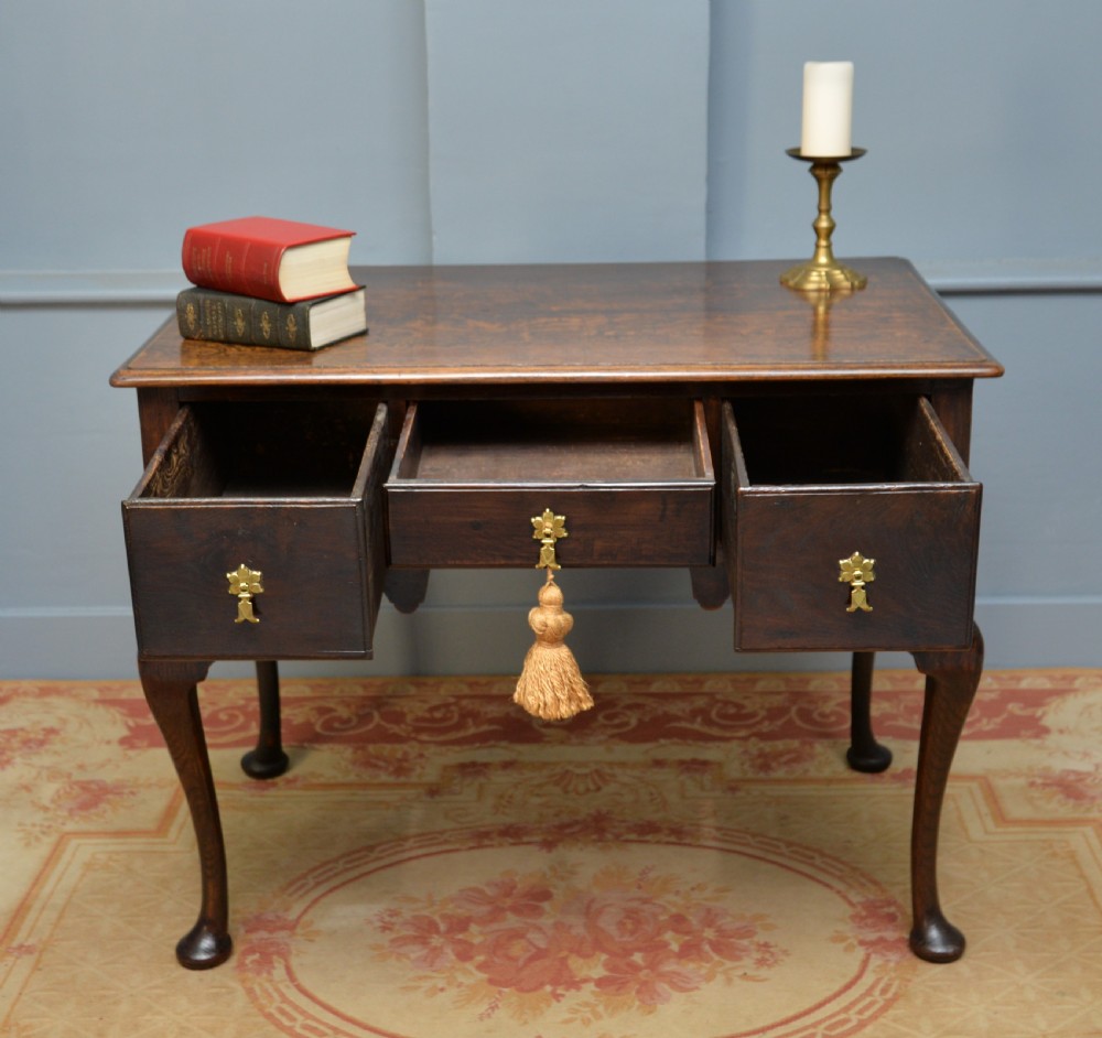 An early 18th-century George I dark oak lowboy featuring three drawers with brass handles, a shaped kneehole apron, and cabriole legs ending in pad feet. View VI