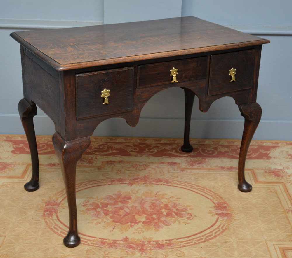 An early 18th-century George I dark oak lowboy featuring three drawers with brass handles, a shaped kneehole apron, and cabriole legs ending in pad feet. View IX