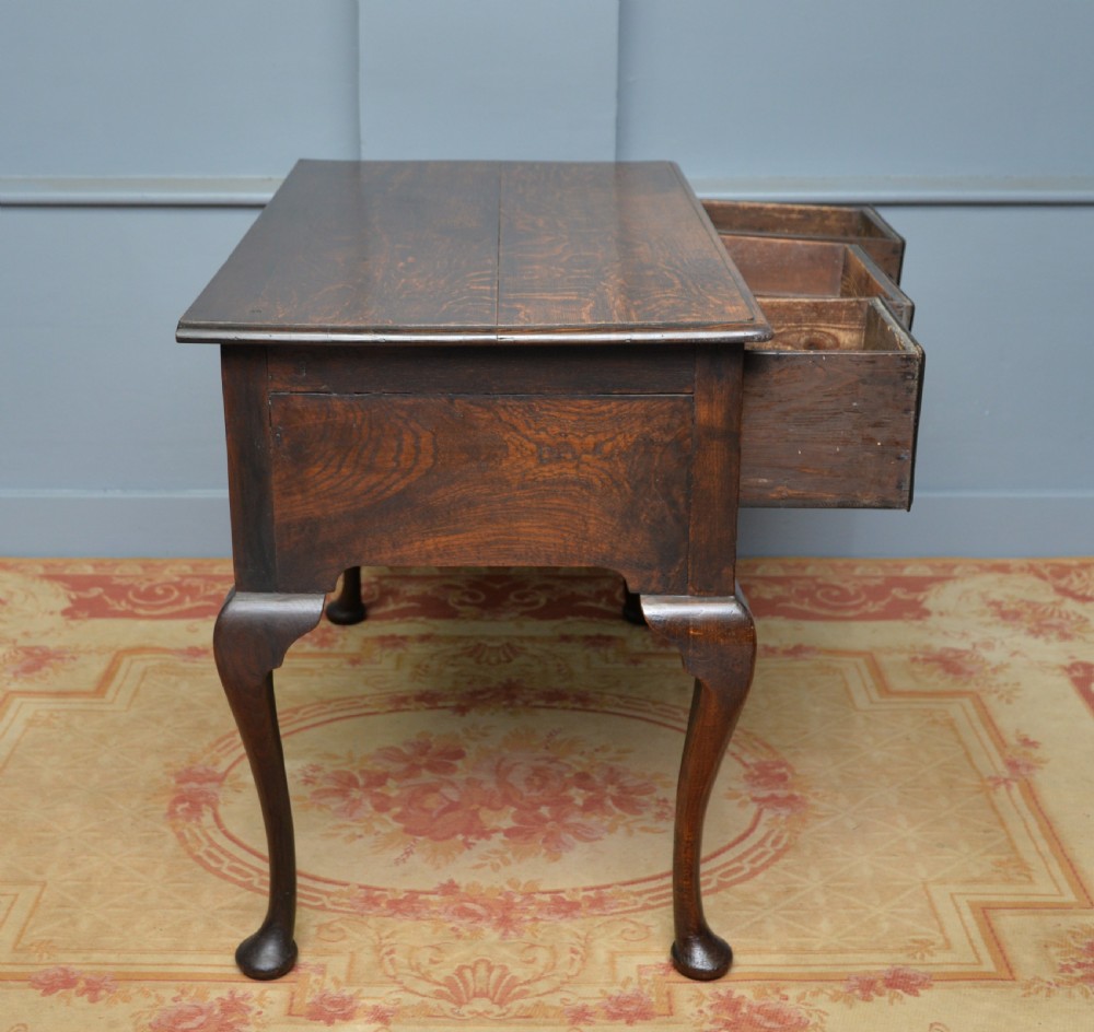 An early 18th-century George I dark oak lowboy featuring three drawers with brass handles, a shaped kneehole apron, and cabriole legs ending in pad feet. View XII