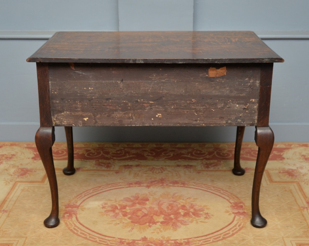 An early 18th-century George I dark oak lowboy featuring three drawers with brass handles, a shaped kneehole apron, and cabriole legs ending in pad feet. View XIII