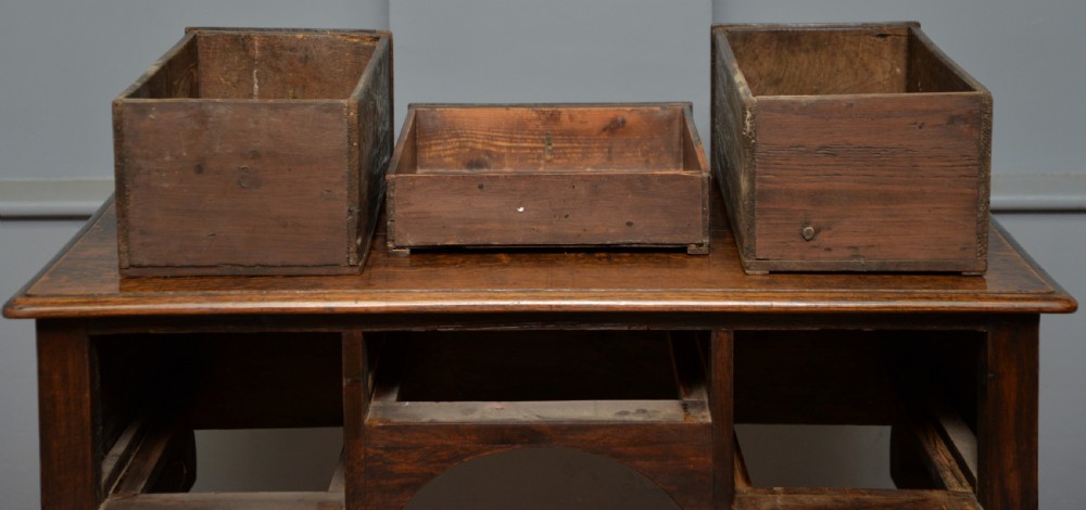 An early 18th-century George I dark oak lowboy featuring three drawers with brass handles, a shaped kneehole apron, and cabriole legs ending in pad feet. View XV
