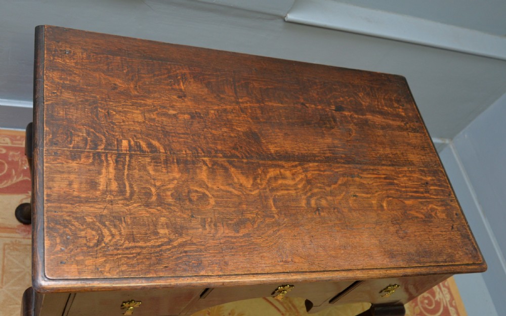 An early 18th-century George I dark oak lowboy featuring three drawers with brass handles, a shaped kneehole apron, and cabriole legs ending in pad feet. View XVI