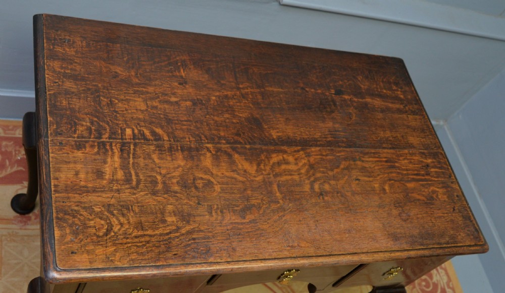 An early 18th-century George I dark oak lowboy featuring three drawers with brass handles, a shaped kneehole apron, and cabriole legs ending in pad feet. View XVII
