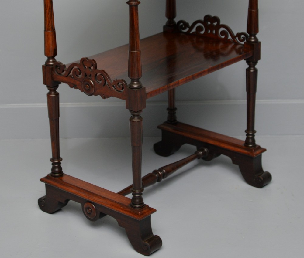 A dark William IV rosewood plant stand with a recessed upper tray, turned support posts, a lower shelf with carved scrollwork, and scroll feet. View X
