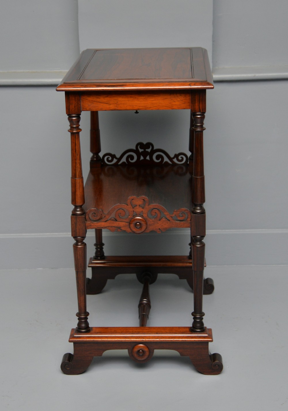 A dark William IV rosewood plant stand with a recessed upper tray, turned support posts, a lower shelf with carved scrollwork, and scroll feet. View XII