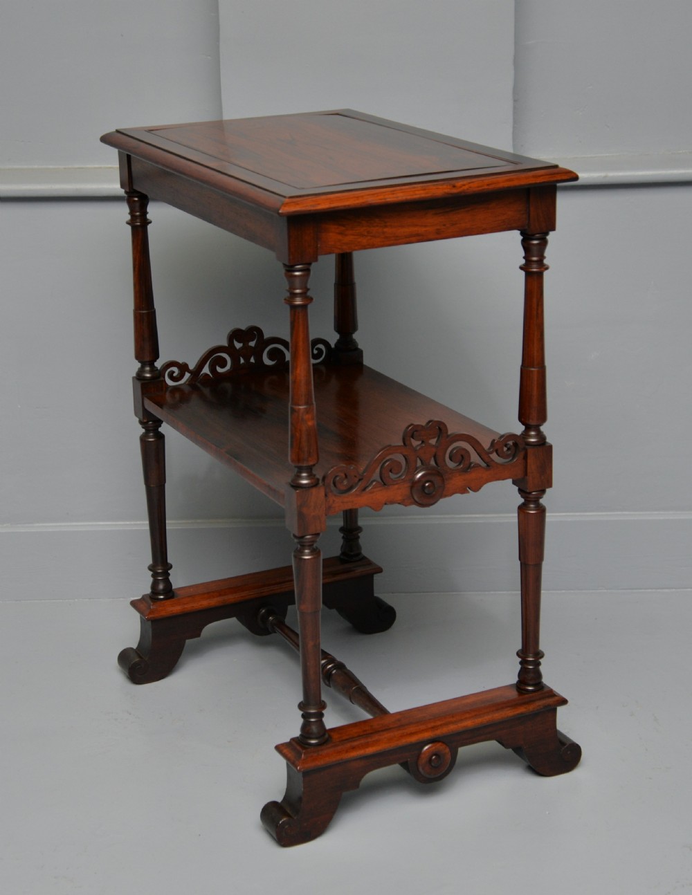A dark William IV rosewood plant stand with a recessed upper tray, turned support posts, a lower shelf with carved scrollwork, and scroll feet. View XIV
