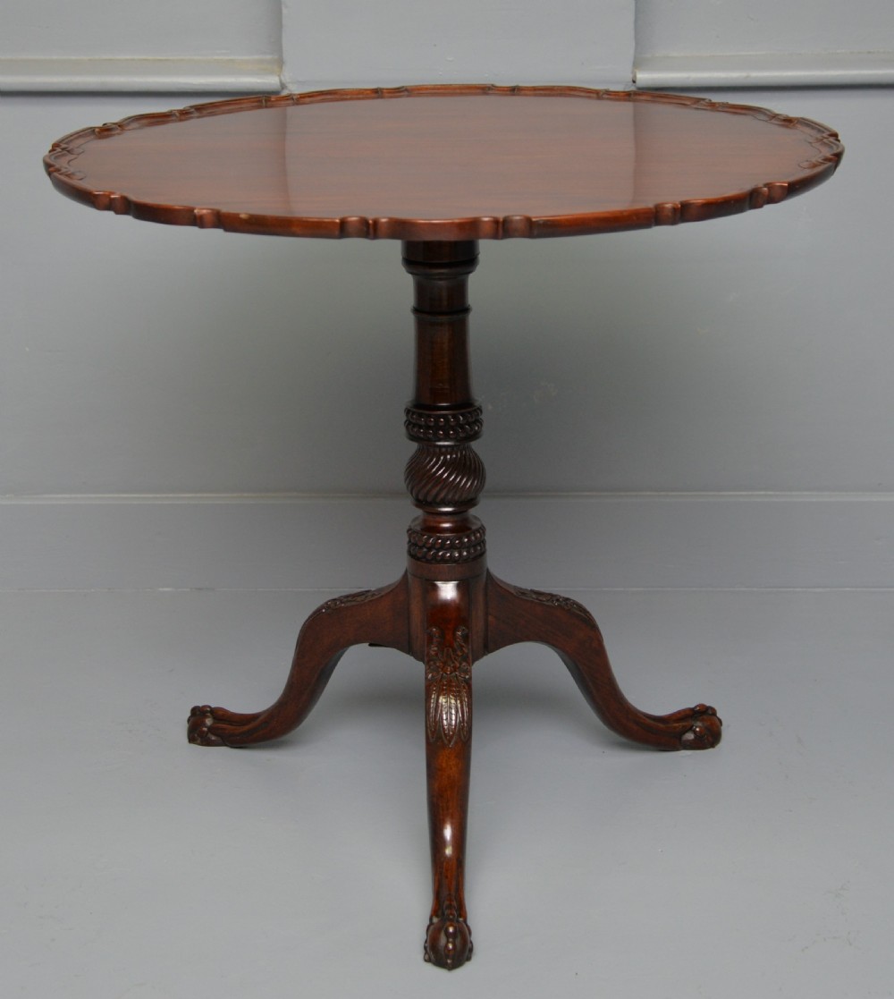 An 18th-century George III mahogany tripod table featuring a circular pie-crust rim, carved turned column, and cabriole legs ending in claw and ball feet.