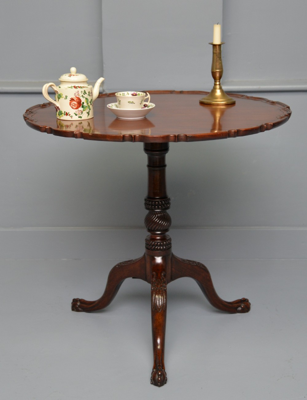An 18th-century George III mahogany tripod table featuring a circular pie-crust rim, carved turned column, and cabriole legs ending in claw and ball feet. View V
