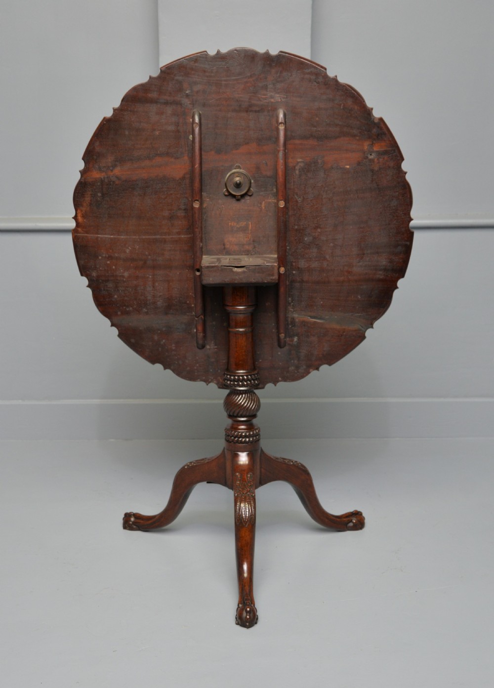 An 18th-century George III mahogany tripod table featuring a circular pie-crust rim, carved turned column, and cabriole legs ending in claw and ball feet. View XVI