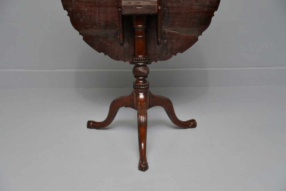 An 18th-century George III mahogany tripod table featuring a circular pie-crust rim, carved turned column, and cabriole legs ending in claw and ball feet. View XVIII