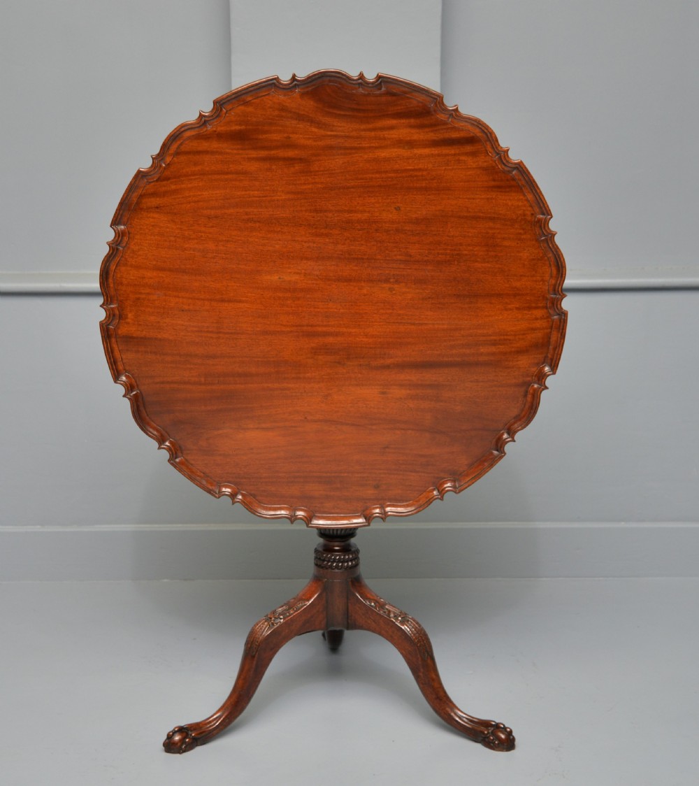 An 18th-century George III mahogany tripod table featuring a circular pie-crust rim, carved turned column, and cabriole legs ending in claw and ball feet. View XXIII