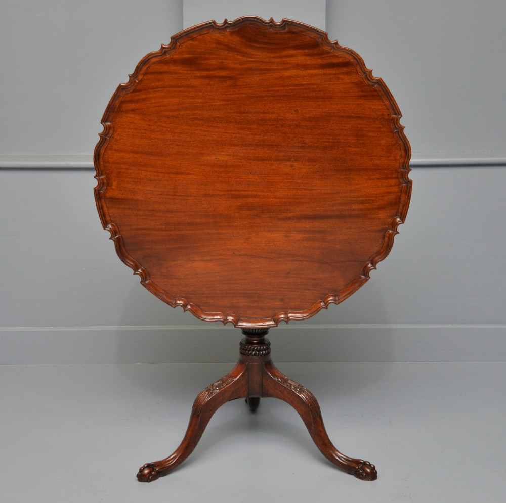 An 18th-century George III mahogany tripod table featuring a circular pie-crust rim, carved turned column, and cabriole legs ending in claw and ball feet. View XXIV