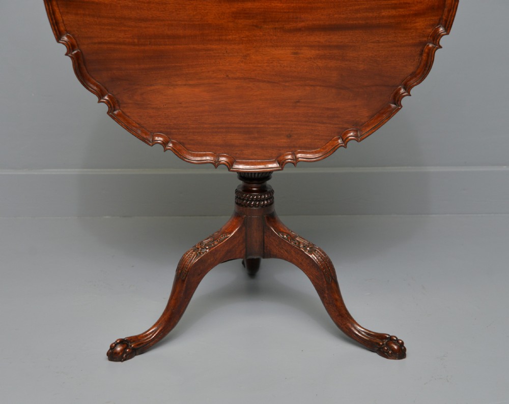 An 18th-century George III mahogany tripod table featuring a circular pie-crust rim, carved turned column, and cabriole legs ending in claw and ball feet. View XXV