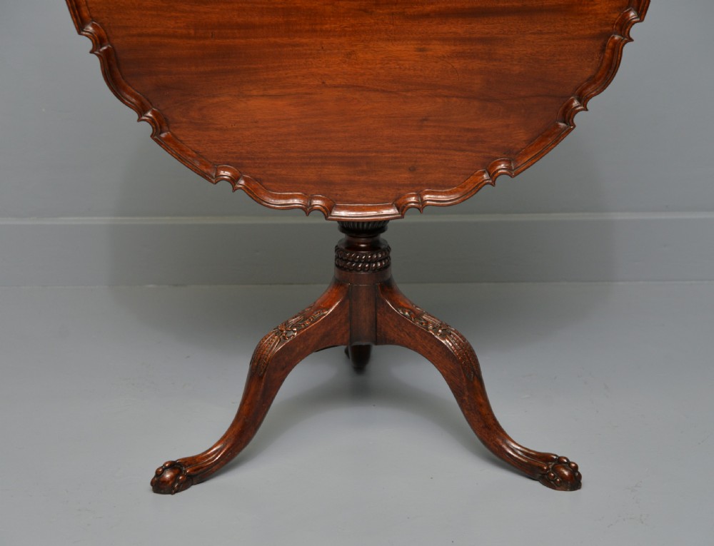 An 18th-century George III mahogany tripod table featuring a circular pie-crust rim, carved turned column, and cabriole legs ending in claw and ball feet. View XXVI