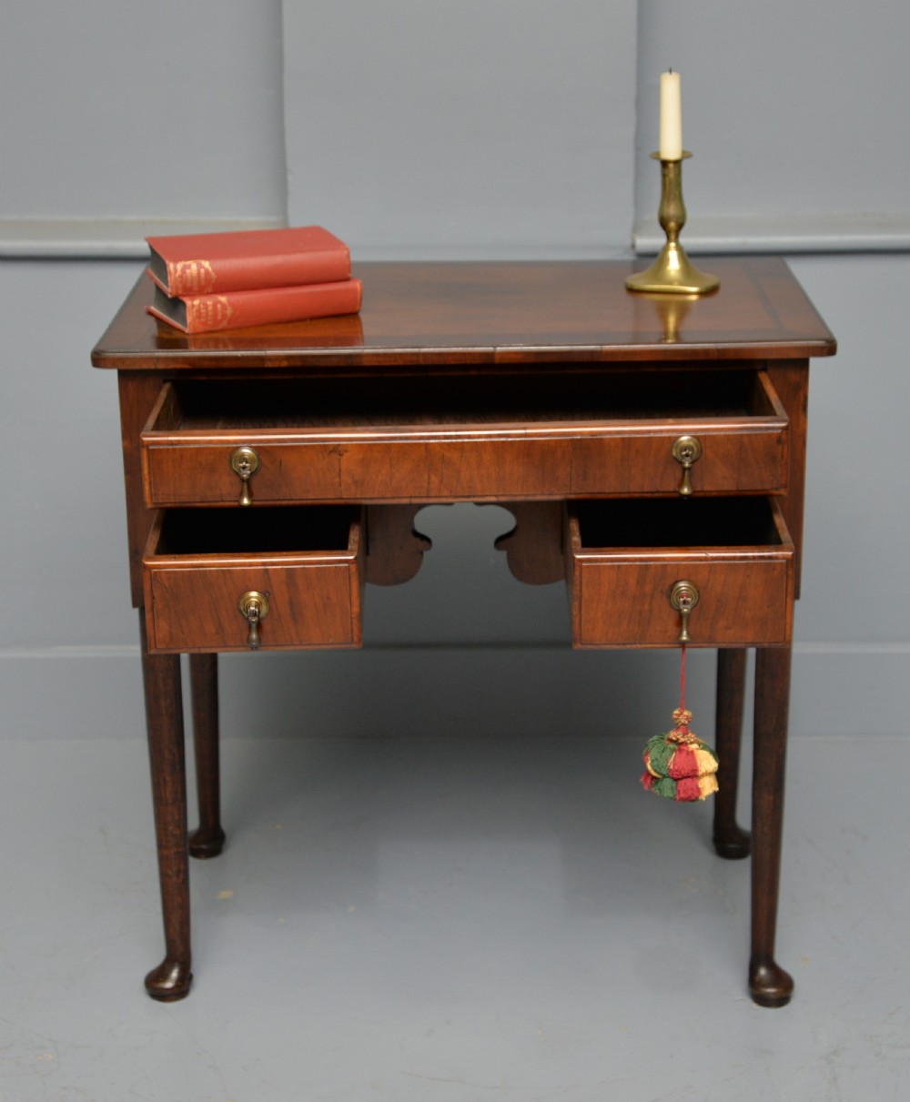 A George II revival walnut lowboy side table featuring three drawers with brass drop handles, a shaped kneehole apron, and slender cabriole legs with pad feet. View II