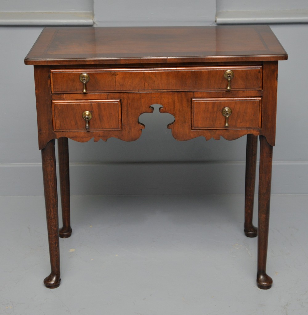 A George II revival walnut lowboy side table featuring three drawers with brass drop handles, a shaped kneehole apron, and slender cabriole legs with pad feet. View III