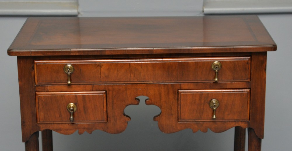 A George II revival walnut lowboy side table featuring three drawers with brass drop handles, a shaped kneehole apron, and slender cabriole legs with pad feet. View V