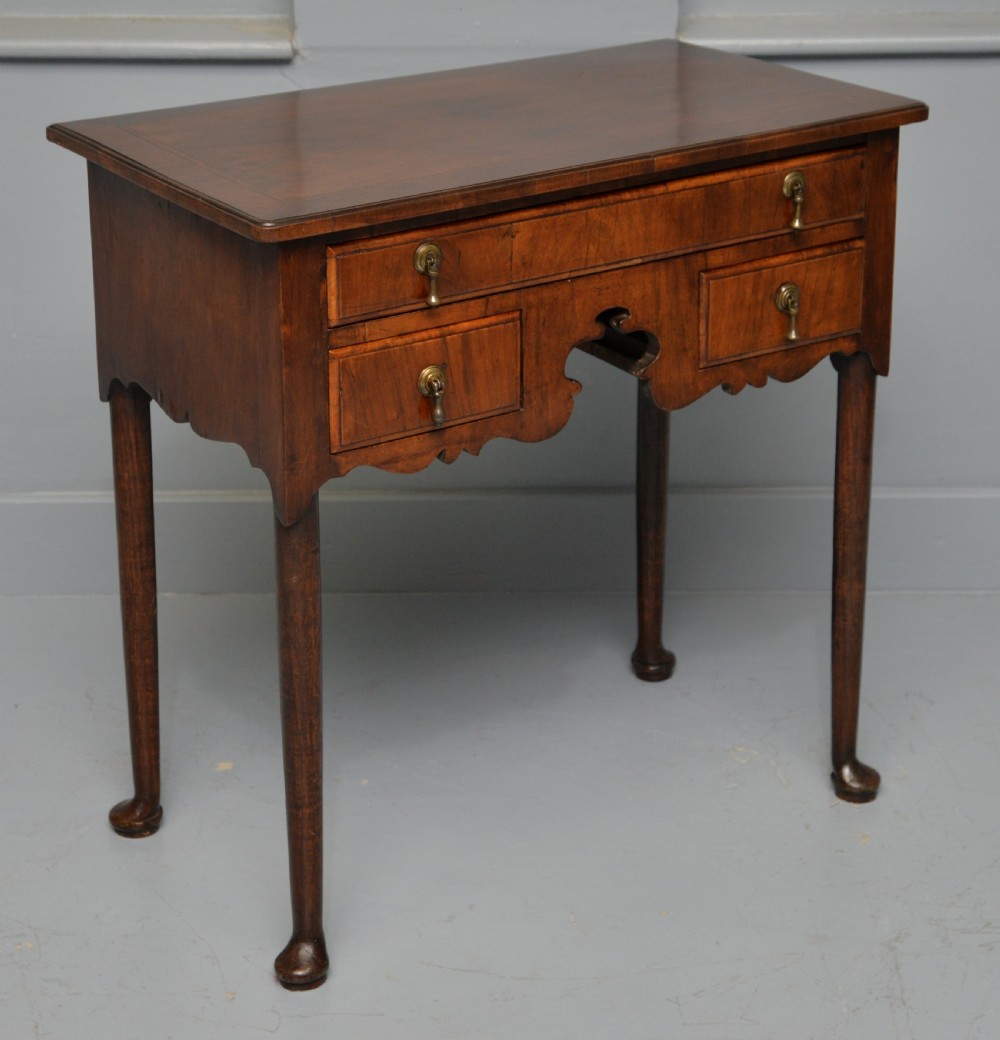 A George II revival walnut lowboy side table featuring three drawers with brass drop handles, a shaped kneehole apron, and slender cabriole legs with pad feet. View VII