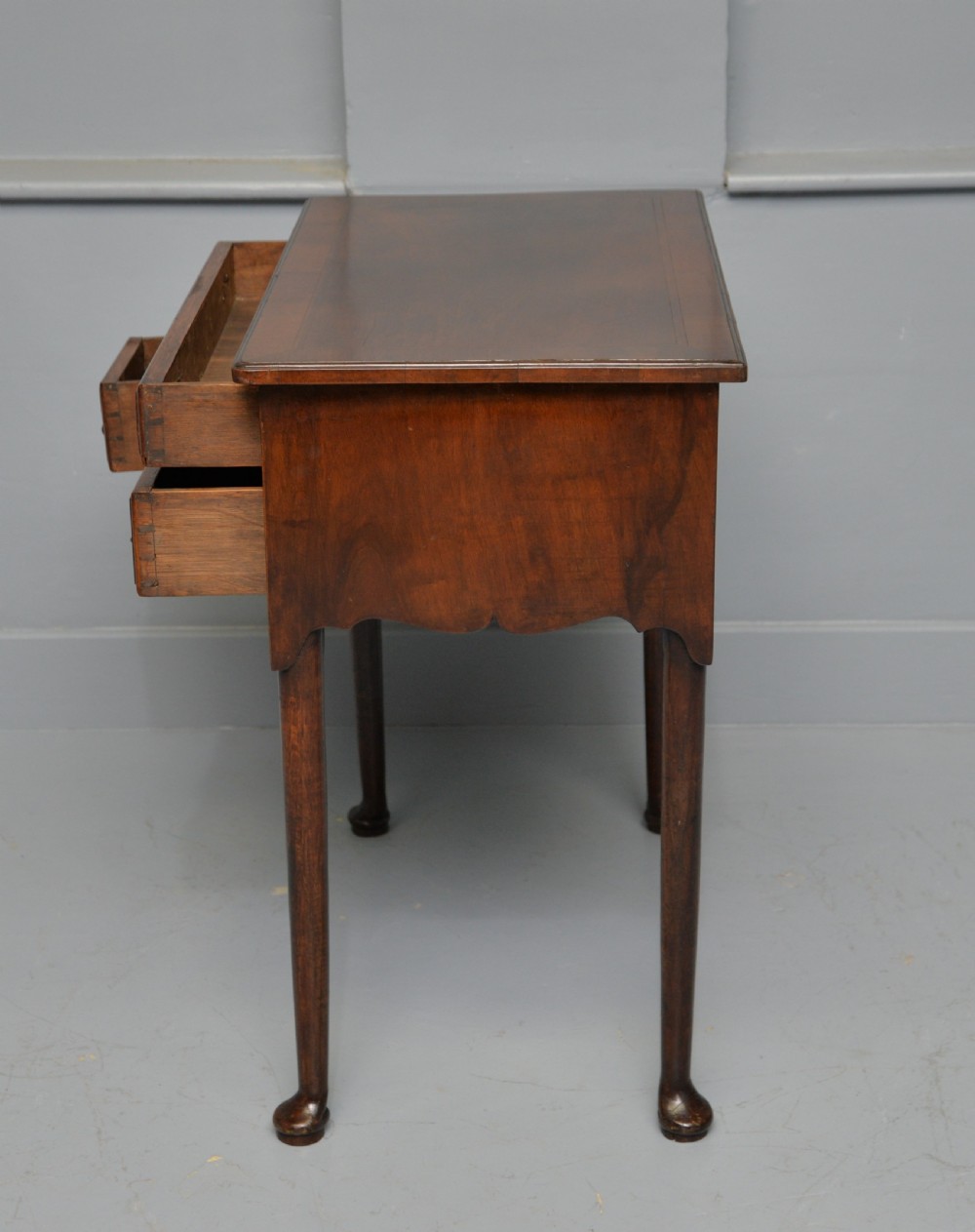 A George II revival walnut lowboy side table featuring three drawers with brass drop handles, a shaped kneehole apron, and slender cabriole legs with pad feet. View XI