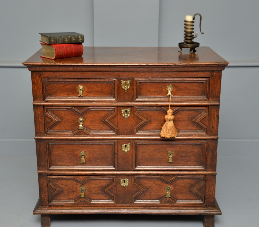 A 17th-century oak chest of drawers featuring geometric panel mouldings across four drawer fronts and brass drop handles. View II