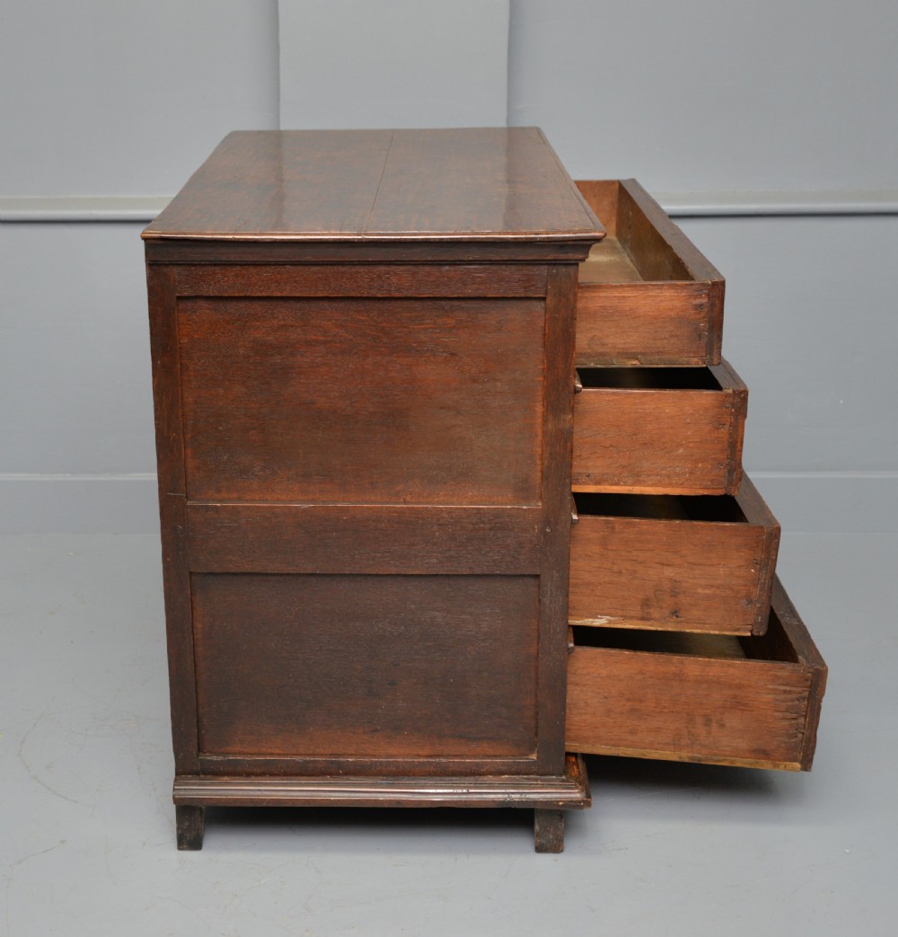A 17th-century oak chest of drawers featuring geometric panel mouldings across four drawer fronts and brass drop handles. View X