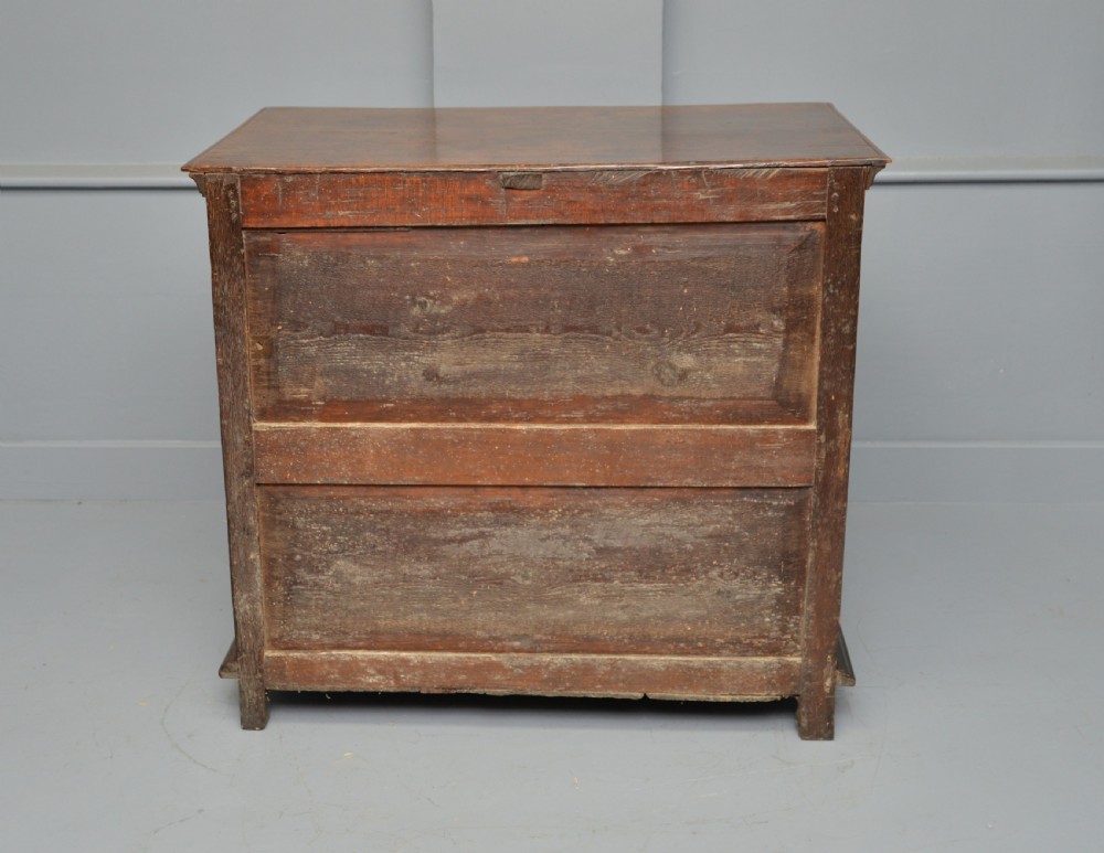 A 17th-century oak chest of drawers featuring geometric panel mouldings across four drawer fronts and brass drop handles. View XI