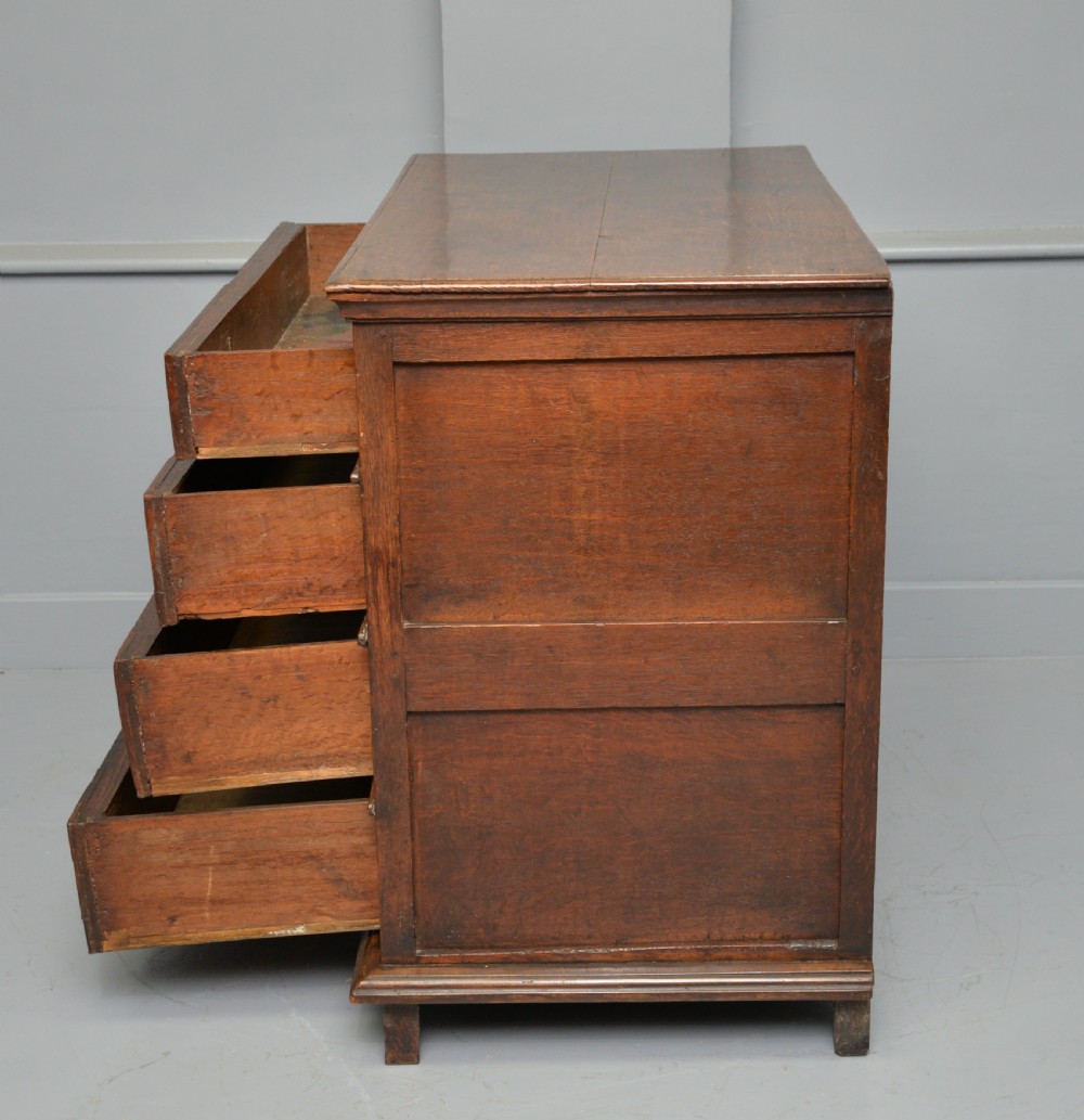 A 17th-century oak chest of drawers featuring geometric panel mouldings across four drawer fronts and brass drop handles. View XII