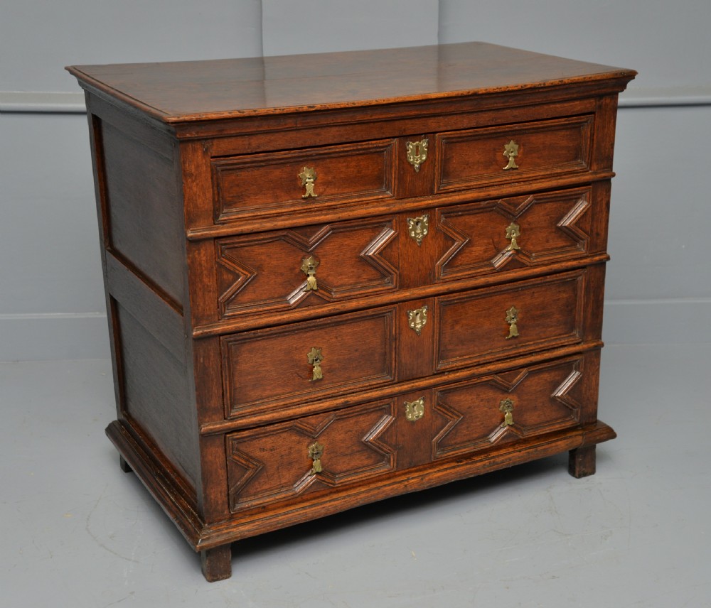 A 17th-century oak chest of drawers featuring geometric panel mouldings across four drawer fronts and brass drop handles. View XIII