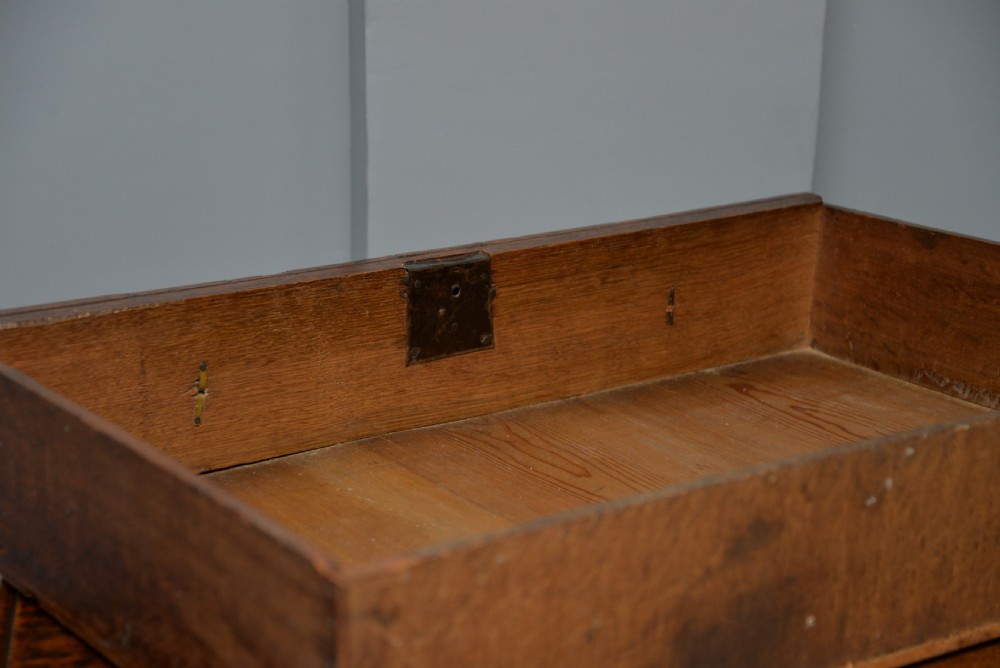 A 17th-century oak chest of drawers featuring geometric panel mouldings across four drawer fronts and brass drop handles. View XV