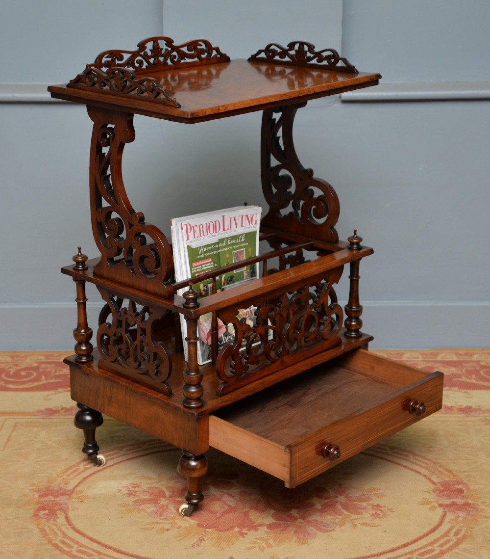A Victorian burr walnut Canterbury table featuring a top shelf with pierced fretwork, lower magazine compartments, a single drawer, and turned legs with ceramic castors. View II