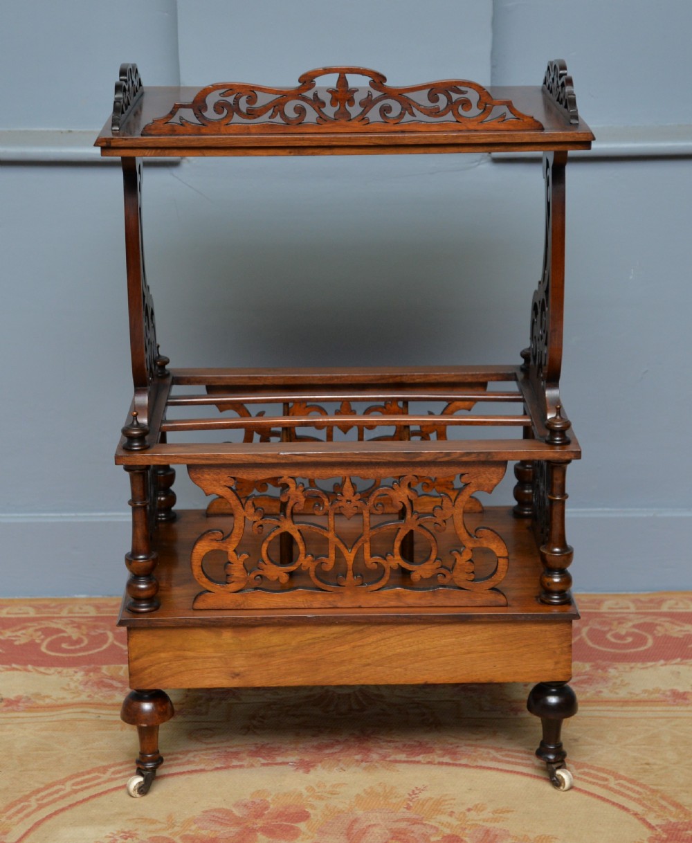A Victorian burr walnut Canterbury table featuring a top shelf with pierced fretwork, lower magazine compartments, a single drawer, and turned legs with ceramic castors. View IX