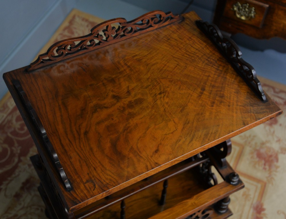 A Victorian burr walnut Canterbury table featuring a top shelf with pierced fretwork, lower magazine compartments, a single drawer, and turned legs with ceramic castors. View XIV