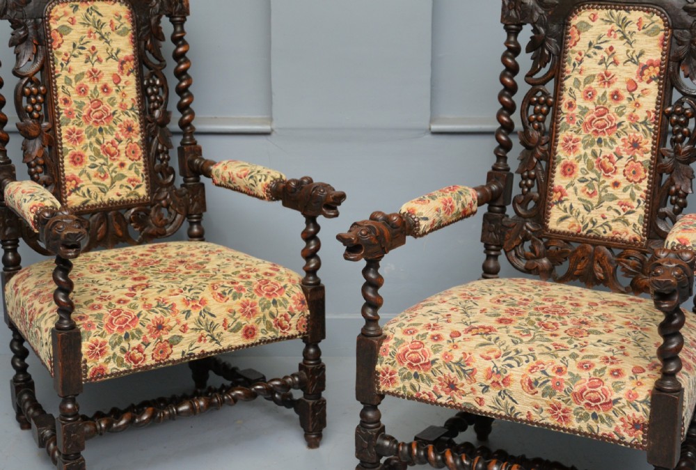 A pair of Victorian dark oak throne chairs featuring Green Man carved crestings, barley twist supports, carved beast armrests, and floral pattern upholstery. View III