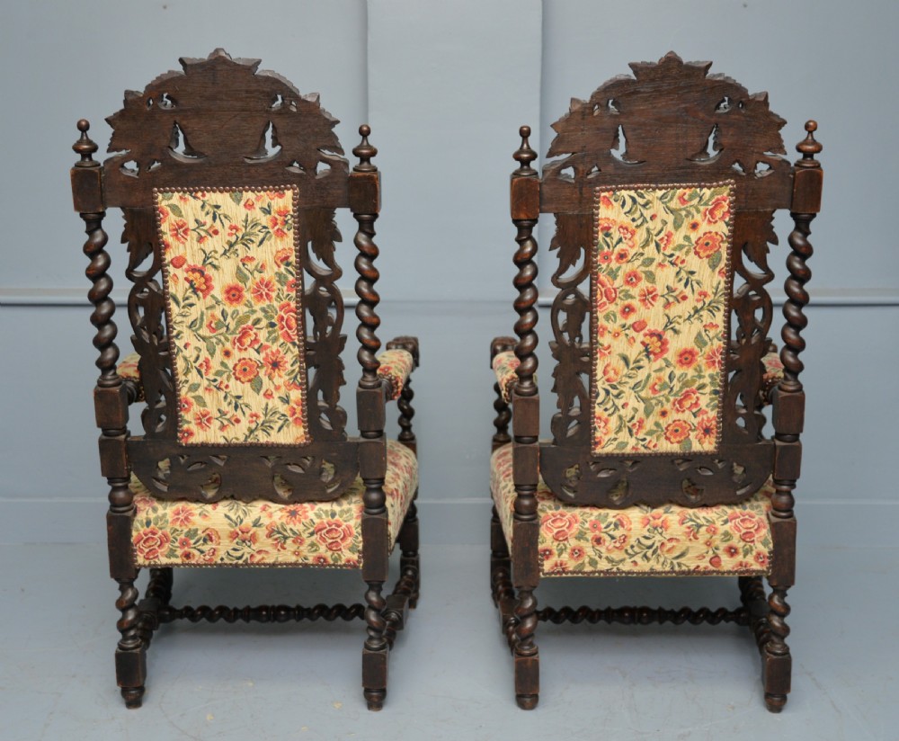 A pair of Victorian dark oak throne chairs featuring Green Man carved crestings, barley twist supports, carved beast armrests, and floral pattern upholstery. View XI