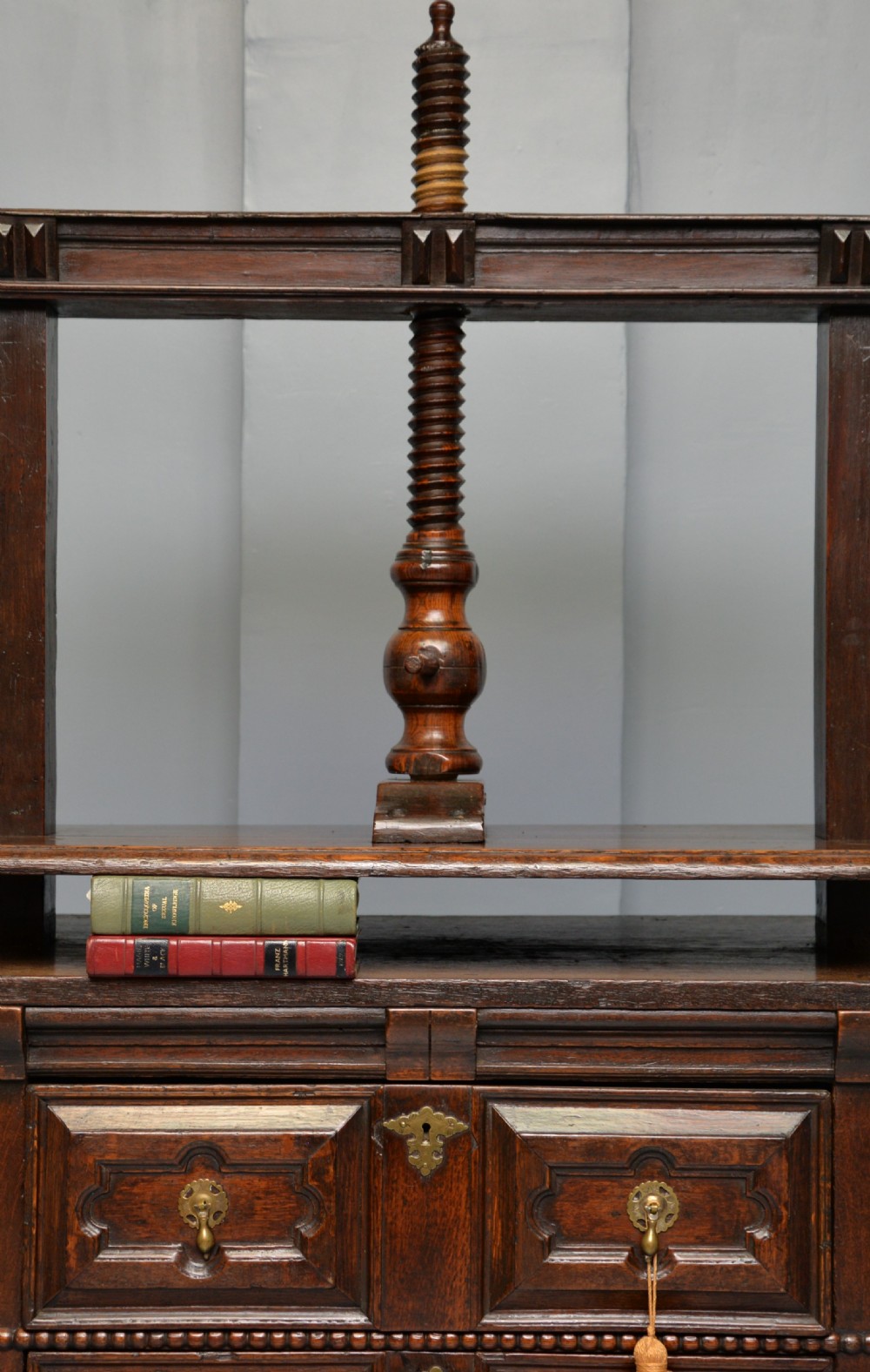 A 17th-century dark oak chest of drawers featuring geometric panelled drawer fronts and an integrated wooden screw linen press mounted on top. View VIII