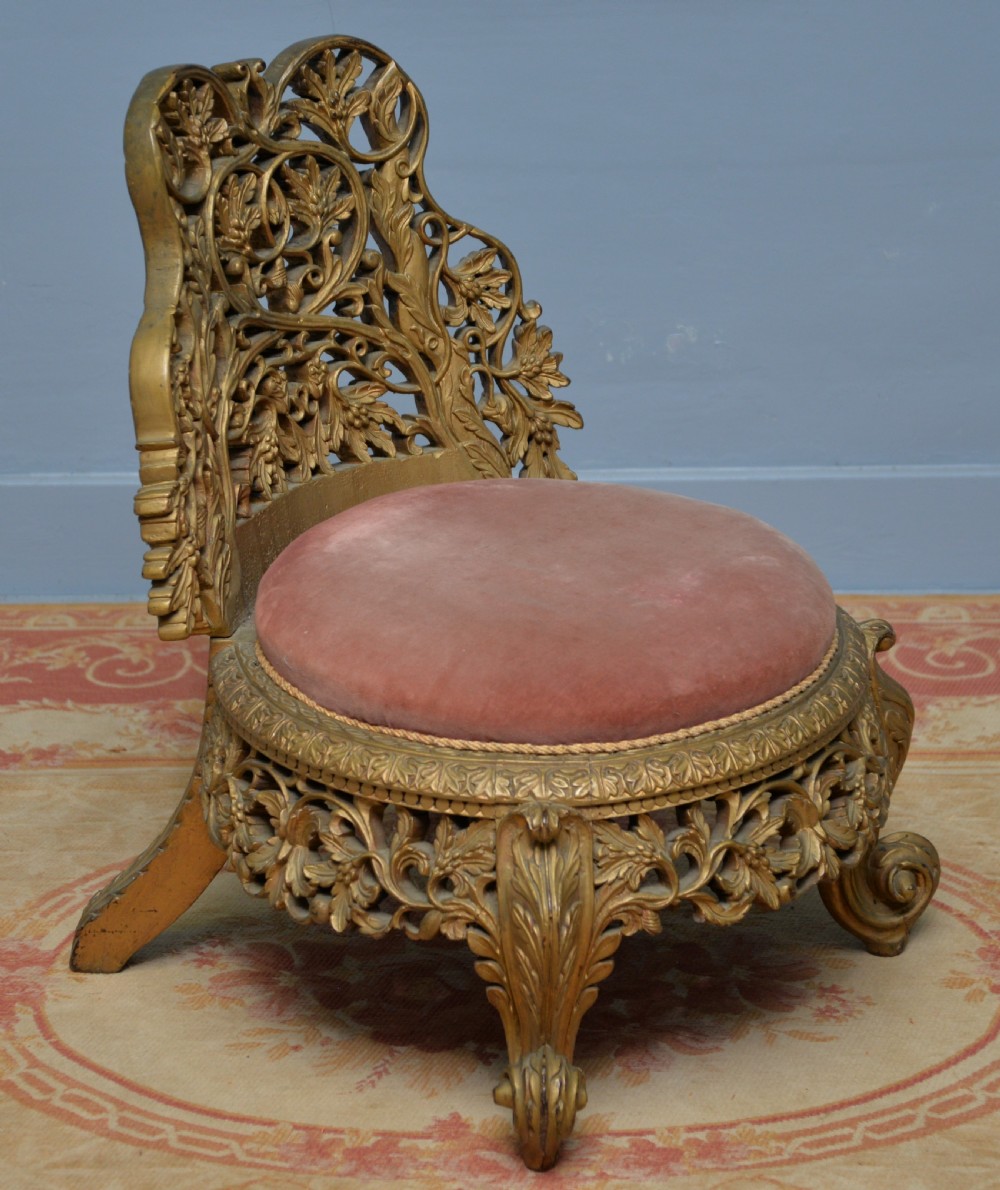 A low 19th-century Anglo-Indian side chair featuring openwork giltwood foliate carving and a round dusty pink velvet seat. View II