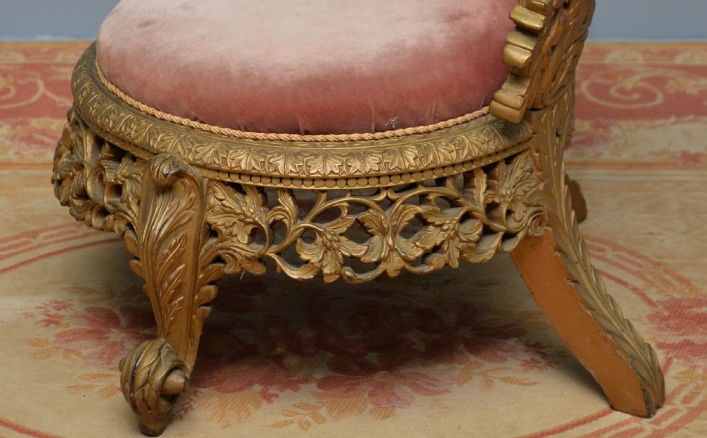A low 19th-century Anglo-Indian side chair featuring openwork giltwood foliate carving and a round dusty pink velvet seat. View IX