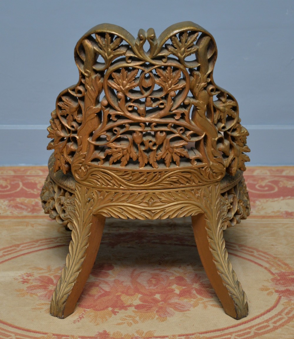 A low 19th-century Anglo-Indian side chair featuring openwork giltwood foliate carving and a round dusty pink velvet seat. View XI