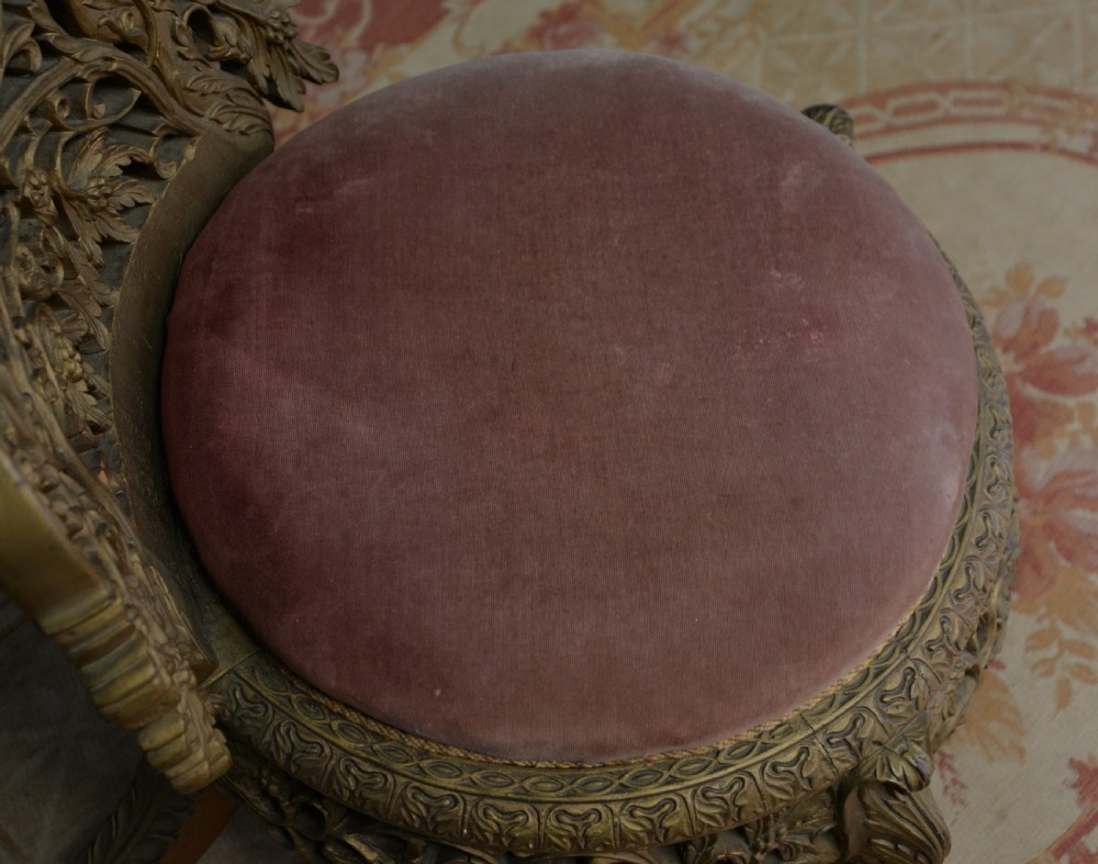 A low 19th-century Anglo-Indian side chair featuring openwork giltwood foliate carving and a round dusty pink velvet seat. View XIV