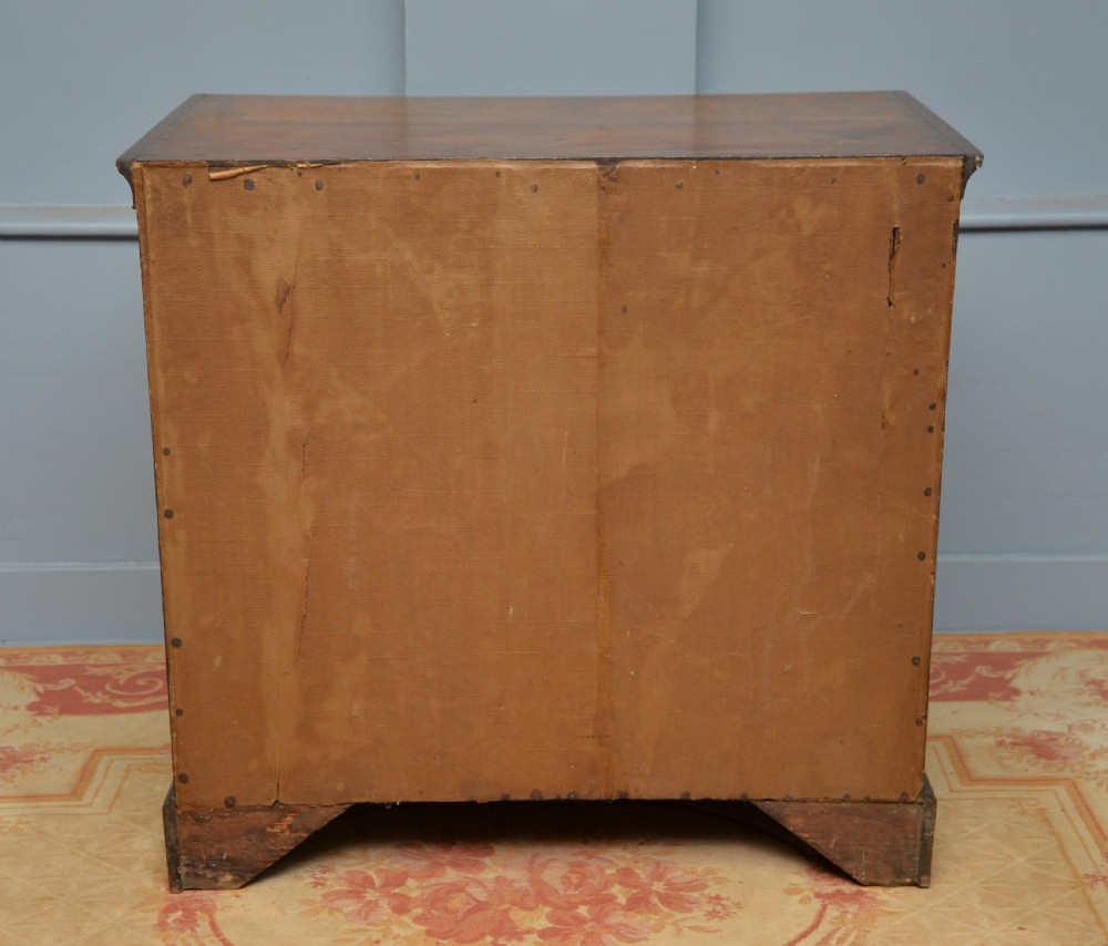A George II solid oak chest of drawers featuring two short over three long graduated drawers with brass drop handles and bracket feet. View X