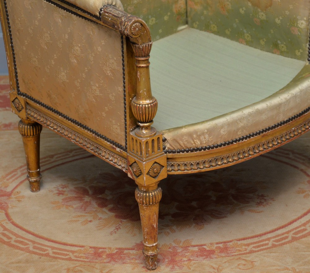 A 19th-century French Louis XVI style bergere armchair with a gilded carved wooden frame, fluted legs, and cream silk damask upholstery. View II