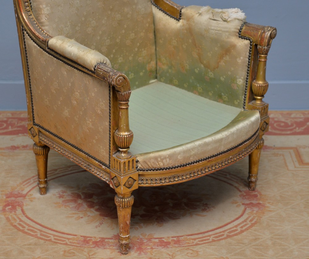 A 19th-century French Louis XVI style bergere armchair with a gilded carved wooden frame, fluted legs, and cream silk damask upholstery. View III