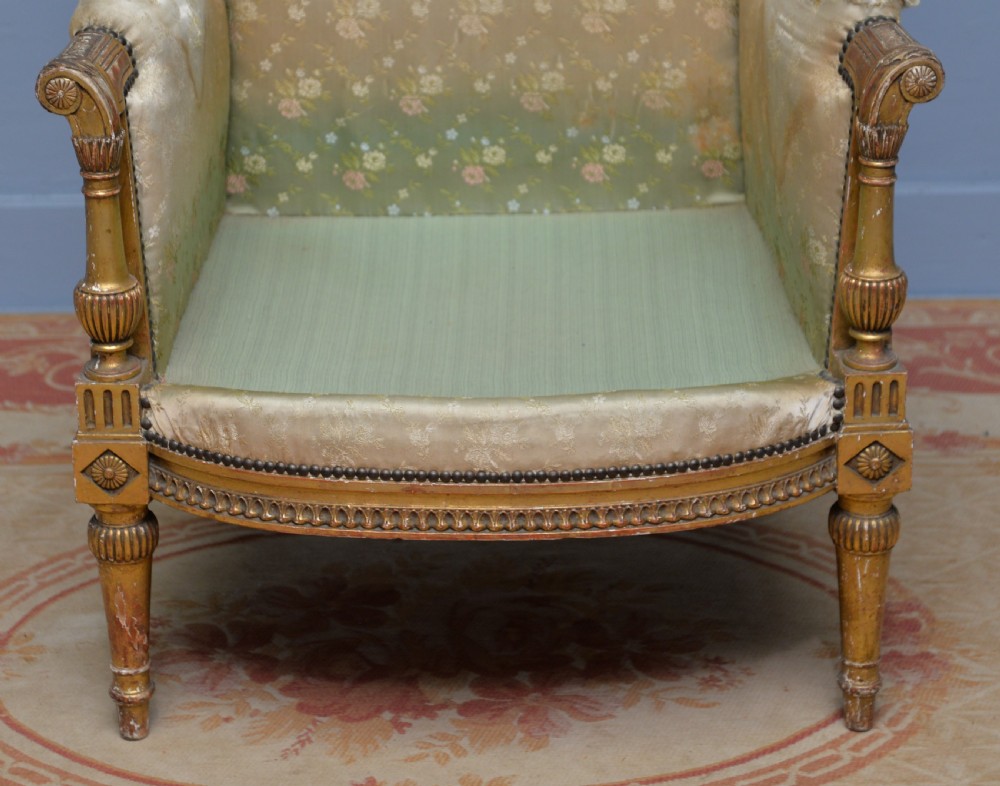 A 19th-century French Louis XVI style bergere armchair with a gilded carved wooden frame, fluted legs, and cream silk damask upholstery. View VII