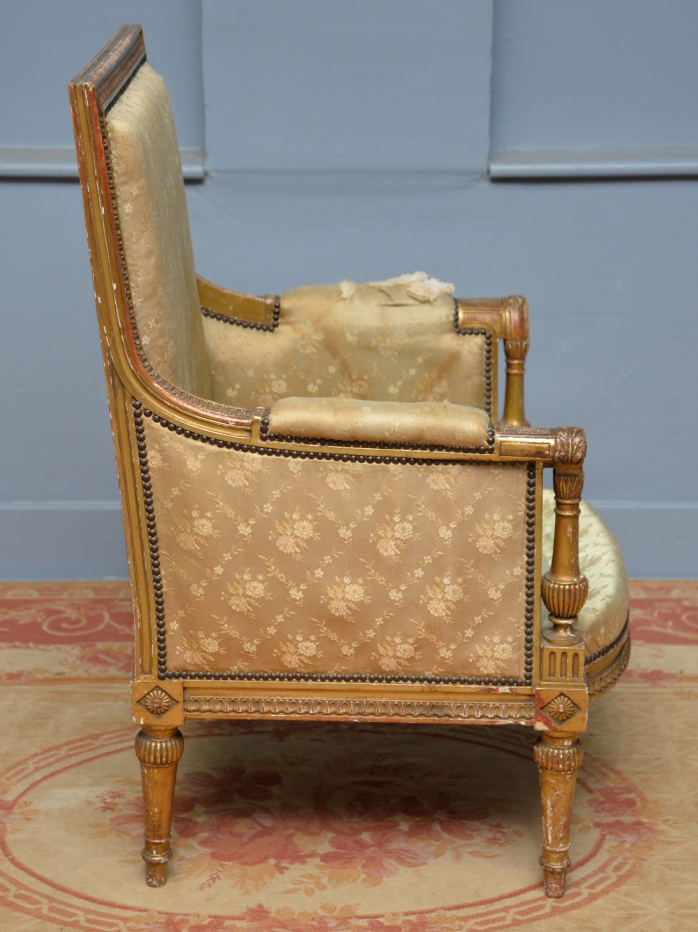 A 19th-century French Louis XVI style bergere armchair with a gilded carved wooden frame, fluted legs, and cream silk damask upholstery. View IX