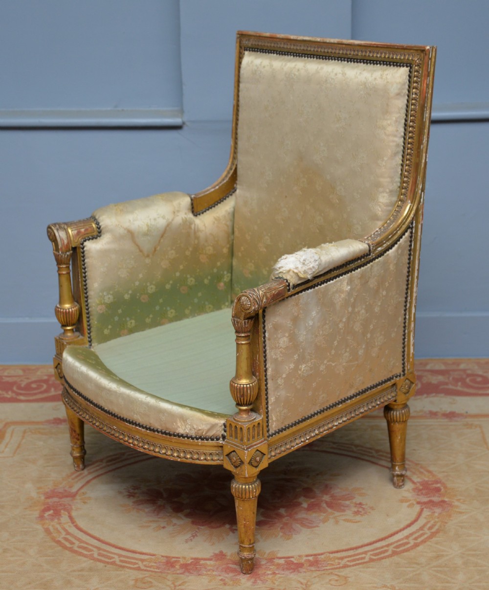 A 19th-century French Louis XVI style bergere armchair with a gilded carved wooden frame, fluted legs, and cream silk damask upholstery. View XIV