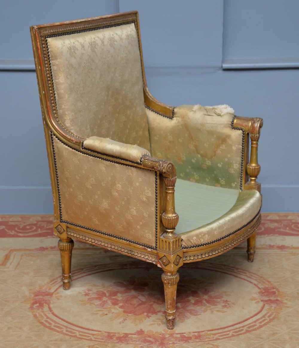 A 19th-century French Louis XVI style bergere armchair with a gilded carved wooden frame, fluted legs, and cream silk damask upholstery. View XV