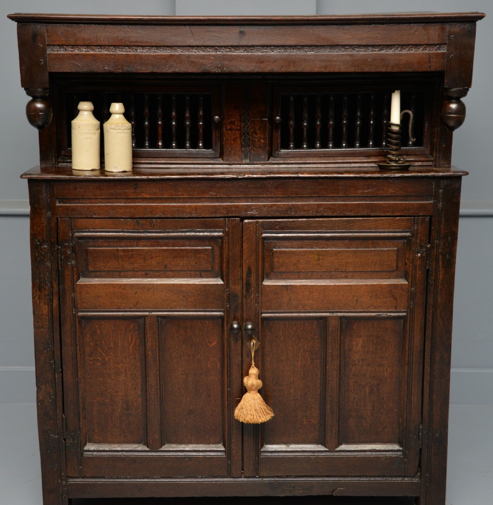 A dark oak 17th-century food court cupboard featuring an upper spindled section with drop finials above a lower two-door panelled cabinet. View III